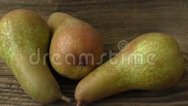 三个成熟多汁的梨子放在深色的木桌上